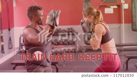 Image of train hard keep fit text over diverse man and woman exercising in gym, boxing Image of train hard keep fit text over diverse man and woman exercising in gym, boxing 117012830