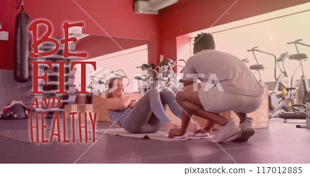 Image of be fit and healthy text over diverse man and woman exercising in gym 117012885