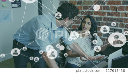 Image of network of connections with icons over diverse colleagues using laptop in office 117013438