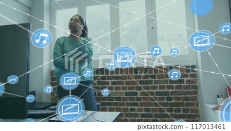 Image of network of connections with icons over biracial businesswoman talking on smartphone 117013461