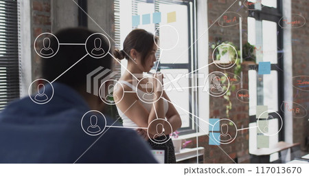 Image of network of connections with icons over diverse colleagues at meeting in office 117013670