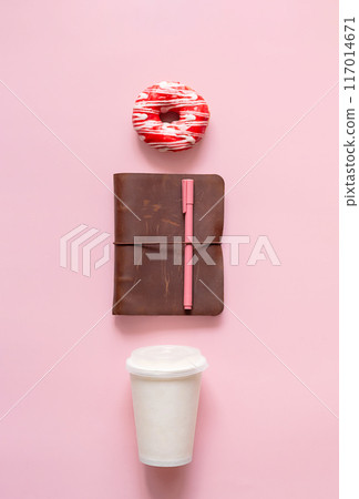 Donut on coffee cup and notebook with pen. Morning routine or study break concept. Donut on coffee cup and notebook with pen. Morning routine or study break concept. 117014671