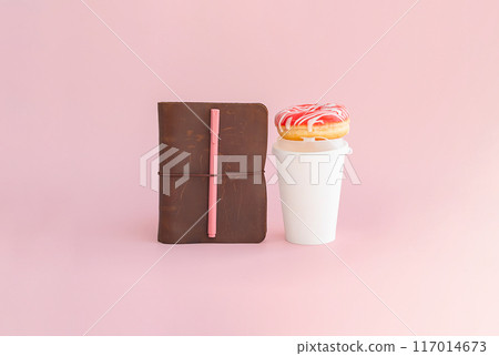 Donut on coffee cup and notebook with pen. Morning routine or study break concept. 117014673