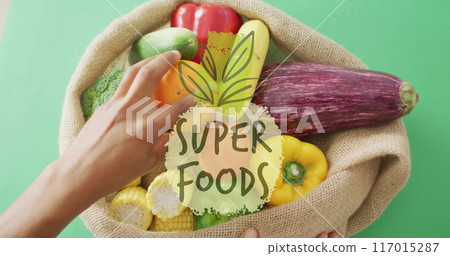 Hands holding burlap sack of vegetables with Super Foods image over it 117015287