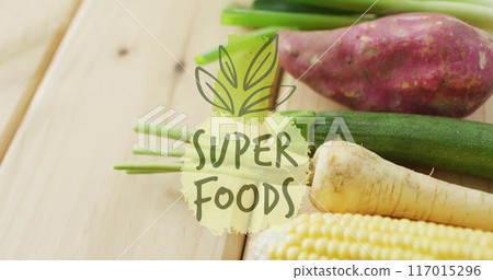 Super foods text image over fresh vegetables on wooden surface 117015296