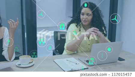 Image of ecology icons over diverse colleagues using laptop and discussing work in office 117015457