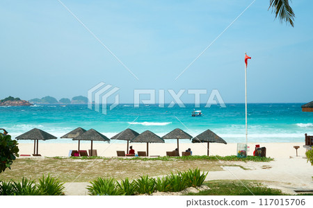 Tourists relaxing under parasols on a tropical beach in malaysia Tourists relaxing under parasols on a tropical beach in malaysia 117015706