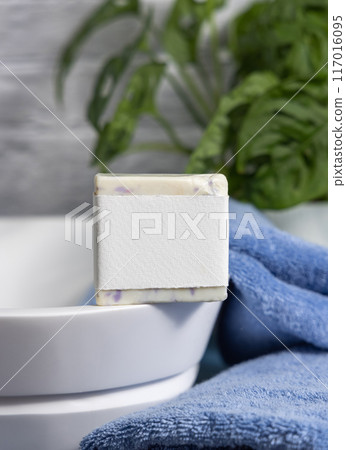 Soap bar with blank label on vessel sink near blue towels and green plant close up, mockup Soap bar with blank label on vessel sink near blue towels and green plant close up, mockup 117016095