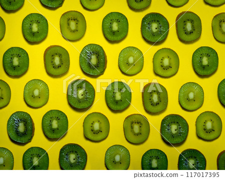 Background of many kiwi slices. Sliced kiwi on a yellow background. Raw food concept. Sliced fruits. Background of many kiwi slices. Sliced kiwi on a yellow background. Raw food concept. Sliced fruits. 117017395