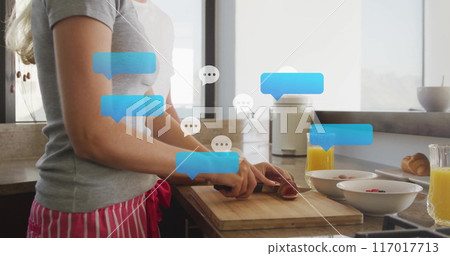 Chopping vegetables in kitchen with chat bubbles image over scene 117017713
