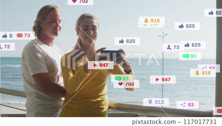 Social media notifications image over people taking selfie by ocean 117017731