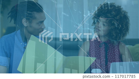 Financial data charts image over two people discussing documents in office 117017785