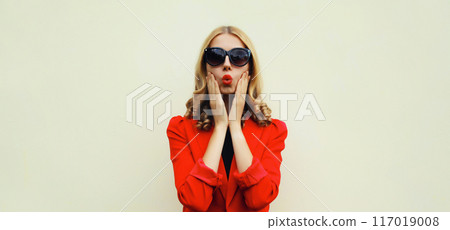 Portrait of beautiful surprised young woman, stylish emotional girl in black glasses, red suit 117019008