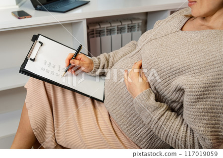 Clad in a snug, textured knit dress that accentuates her baby bump 117019059