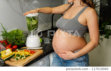 Pregnant woman putting raw ingredients into a blender to make smoothie Pregnant woman putting raw ingredients into a blender to make smoothie 117019060
