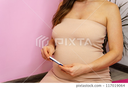 Embracing the joy of impending motherhood, a serene pregnant woman in a soft 117019064