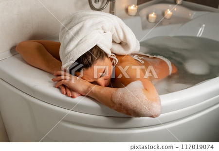 Pregnant woman in bubble bath with candles 117019074