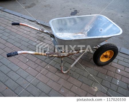 wheelbarrow is on the cobblestones. Construction accessory. Tool for transporting sand and cement. Construction and repair work. wheelbarrow is on the cobblestones. Construction accessory. Tool for transporting sand and cement. Construction and repair work. 117020330