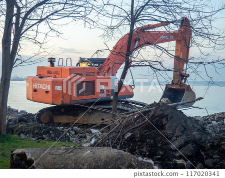 Excavator work at night. Overtime work. The work of construction equipment on the seashore. Batumi. Fortified shores. at sunset. Hitachi Excavator work at night. Overtime work. The work of construction equipment on the seashore. Batumi. Fortified shores. at sunset. Hitachi 117020341