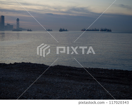 Foggy sea horizon with ships and city silhouette. Evening Batumi. Georgia. Beautiful gray landscape. 117020343