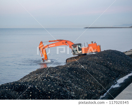Excavator work at night. Overtime work. The work of construction equipment on the seashore. Batumi. Fortified shores. at sunset. Hitachi Excavator work at night. Overtime work. The work of construction equipment on the seashore. Batumi. Fortified shores. at sunset. Hitachi 117020345
