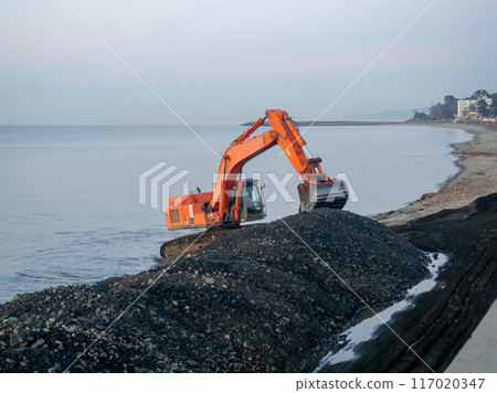 Excavator work at night. Overtime work. The work of construction equipment on the seashore. Batumi. Fortified shores. at sunset. Excavator work at night. Overtime work. The work of construction equipment on the seashore. Batumi. Fortified shores. at sunset. 117020347