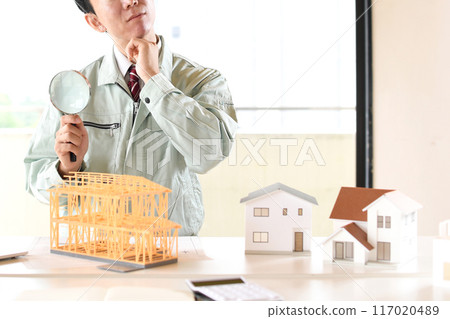 一名拿著放大鏡的男工在建築模型前憂心忡忡 一名拿著放大鏡的男工在建築模型前憂心忡忡 117020489