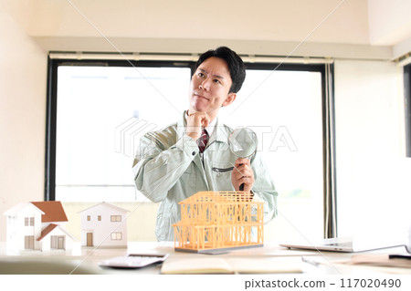 一名拿著放大鏡的男工在建築模型前憂心忡忡 一名拿著放大鏡的男工在建築模型前憂心忡忡 117020490