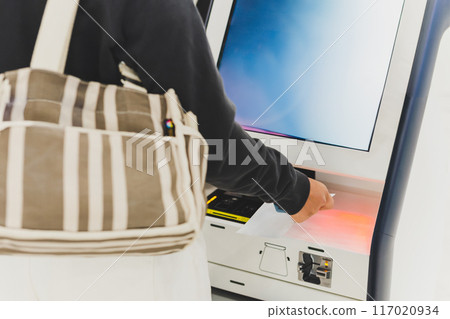 Woman passenger doing self check in scanning boarding pass at airport. 117020934
