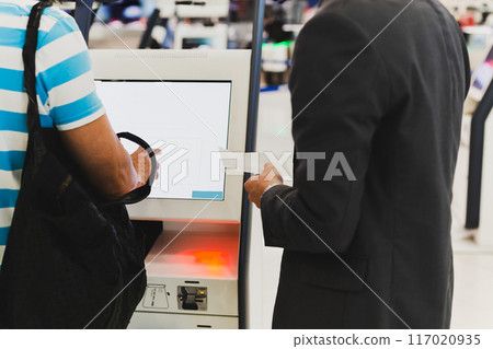Male passenger with backpack  doing self check in for flight at automatic device in modern airport. 117020935