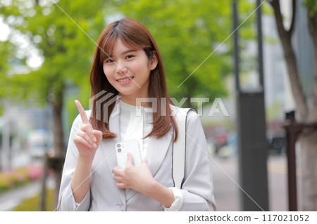 Business woman holding a smartphone and posing for one point_2 117021052