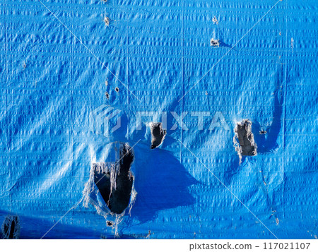 Blue canvas with holes. Leaky fabric. Forgotten. Abandoned. Blue canvas with holes. Leaky fabric. Forgotten. Abandoned. 117021107