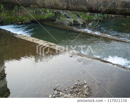Heating main over the stream. Industry and nature.   Concrete rapids on the river 117021138