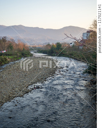 A shallow fast river. Stream with shallows. Fast river in the city. Concrete rapids on the river. River in Georgia. 117021141