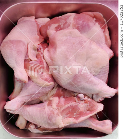 Raw chicken thighs placed in stainless steel compartments are available in supermarkets. 117022252