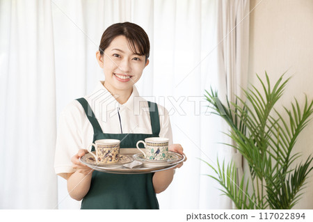 Smiling female cafe staff bringing cold drinks Smiling female cafe staff bringing cold drinks 117022894