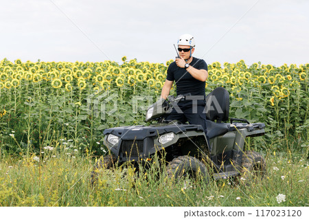 The rescuer, a beautiful athletic physique, rides an ATV in the middle of the field The rescuer, a beautiful athletic physique, rides an ATV in the middle of the field 117023120