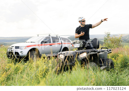 The rescuer, a beautiful athletic physique, rides an ATV in the middle of the field The rescuer, a beautiful athletic physique, rides an ATV in the middle of the field 117023124