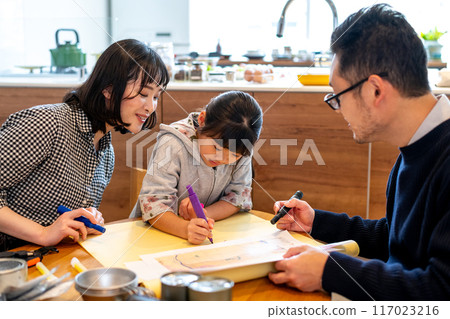 一位母親微笑著看著女兒在一張大紙上寫下疏散地點。 一位母親微笑著看著女兒在一張大紙上寫下疏散地點。 117023216