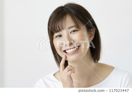 A portrait of a woman in her early 30s with beautiful straight teeth, smiling and looking at the camera A portrait of a woman in her early 30s with beautiful straight teeth, smiling and looking at the camera 117023447
