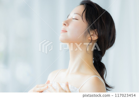 A young woman feels her skin become more moisturized A young woman feels her skin become more moisturized 117023454