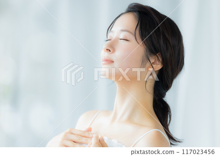 A young woman feels her skin become more moisturized 117023456