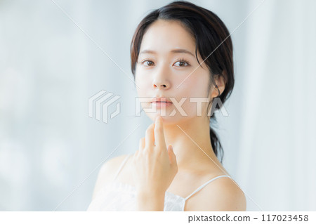 A young woman feels her skin become more moisturized A young woman feels her skin become more moisturized 117023458