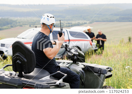 The rescuer, a beautiful athletic physique, rides an ATV in the middle of the field 117024253