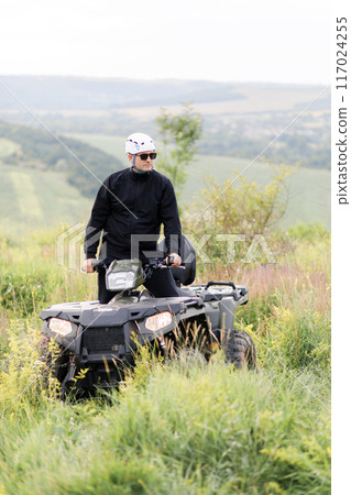 The rescuer, a beautiful athletic physique, rides an ATV in the middle of the field 117024255