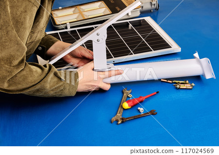 Solar panel and LED light are prepared for installation on mounting bracket, DIY street lighting assembly. 117024569