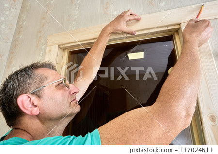 Creating marking door frame using pencil and piece of trim. 117024611