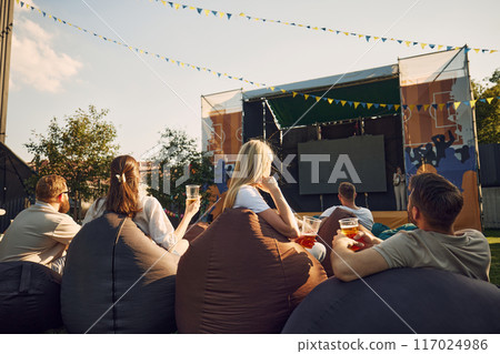 Music festival, Group of people, men and women, friends gathering outdoor to on warm summer day, drinking beer, watching concert 117024986