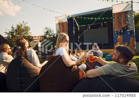 Music festival, Group of people, men and women, friends gathering outdoor to on warm summer day, drinking beer, watching concert Music festival, Group of people, men and women, friends gathering outdoor to on warm summer day, drinking beer, watching concert 117024988