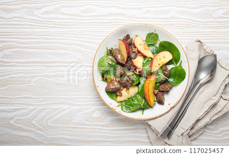 Healthy Salad with Iron Rich Ingredients Chicken Liver, Apples, Fresh Spinach and Walnuts on White Ceramic Plate, White Wooden Background Top View. 117025457